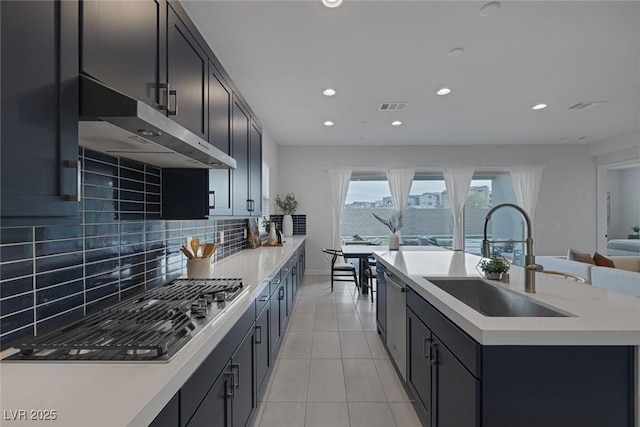 kitchen featuring sink, light tile patterned floors, an island with sink, stainless steel appliances, and backsplash