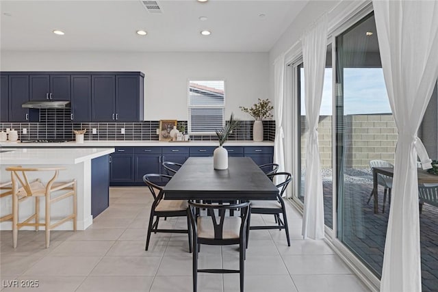 kitchen with tasteful backsplash, blue cabinetry, light tile patterned floors, and a kitchen bar