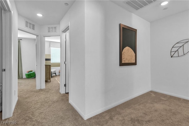 hall featuring carpet, visible vents, and baseboards