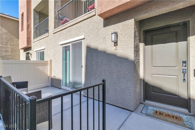 property entrance with a balcony and stucco siding