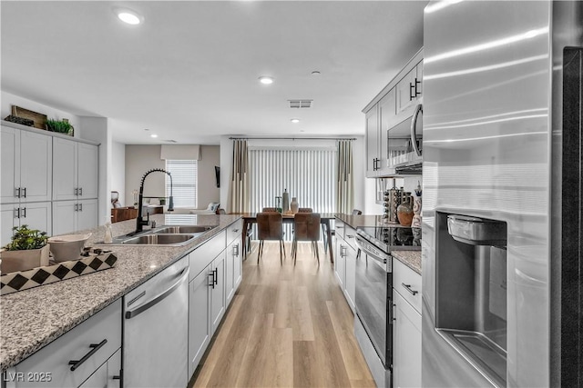 kitchen featuring light wood finished floors, stainless steel appliances, recessed lighting, visible vents, and a sink