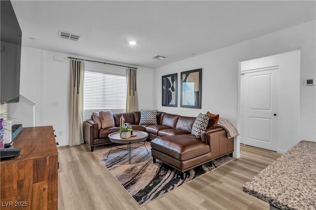 living area with light wood-style flooring and visible vents