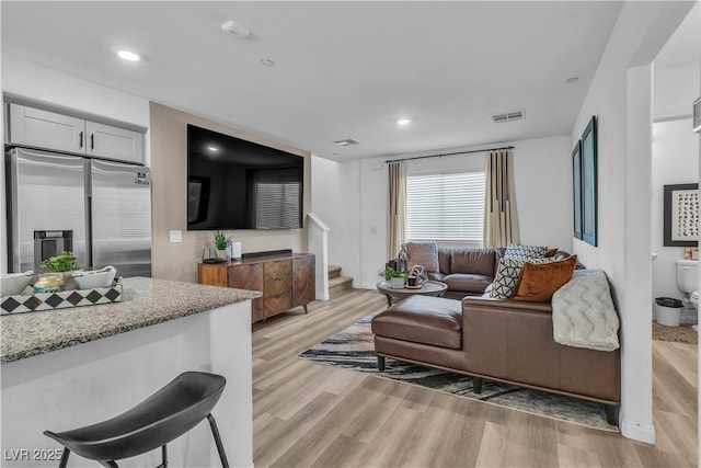 living area with light wood-type flooring, stairway, visible vents, and recessed lighting