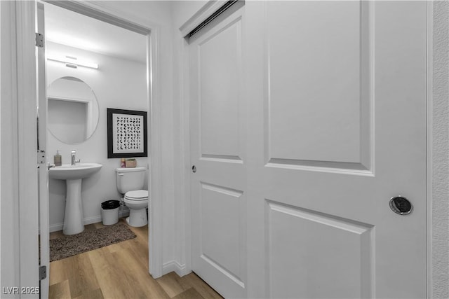 bathroom with a sink, wood finished floors, toilet, and baseboards