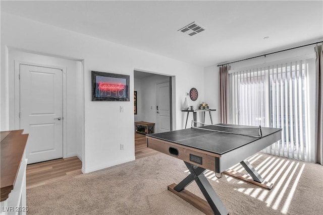 recreation room with light carpet, visible vents, and baseboards