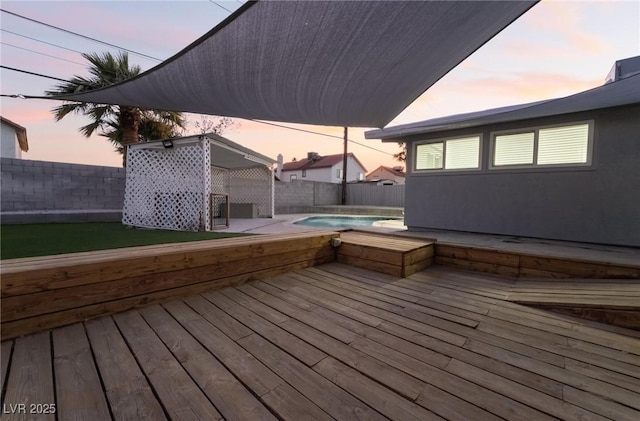 deck at dusk featuring a fenced in pool