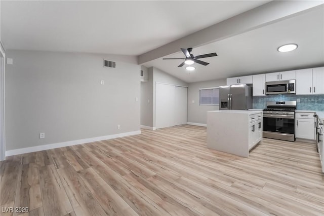 kitchen featuring tasteful backsplash, lofted ceiling with beams, appliances with stainless steel finishes, light hardwood / wood-style floors, and white cabinets