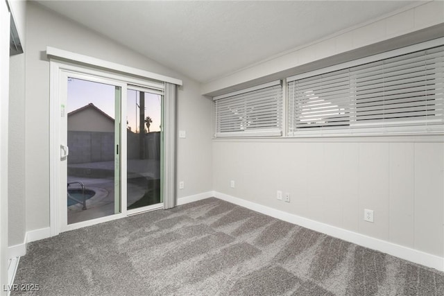 carpeted spare room featuring vaulted ceiling