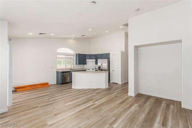 kitchen with sink, a kitchen island, light hardwood / wood-style floors, and appliances with stainless steel finishes