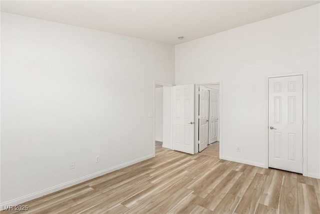 empty room with a towering ceiling and light wood-type flooring