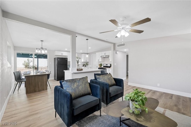 living room with lofted ceiling, ceiling fan with notable chandelier, and light hardwood / wood-style flooring