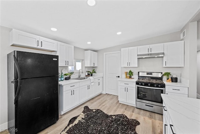 kitchen featuring black refrigerator, white cabinetry, stainless steel range with gas cooktop, and sink