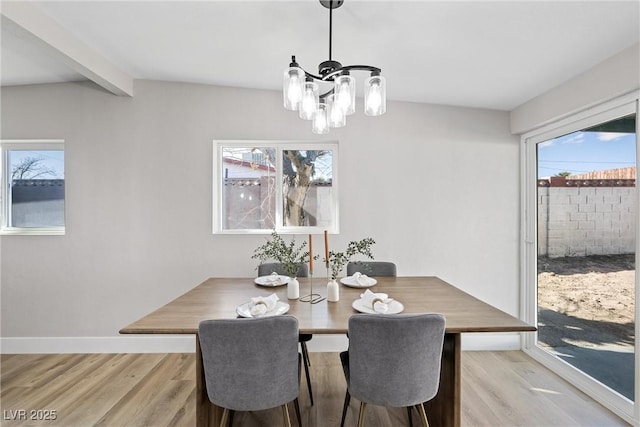 dining space with beam ceiling, an inviting chandelier, and light wood-type flooring