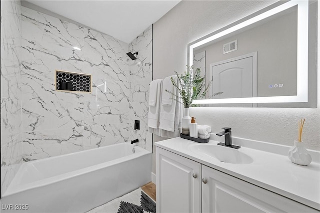 bathroom with tiled shower / bath combo and vanity