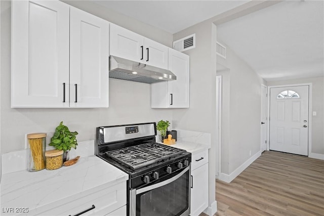 kitchen with white cabinetry, stainless steel gas range, light stone counters, and light wood-type flooring