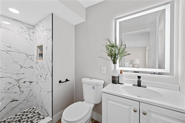 bathroom with vanity, toilet, and a tile shower