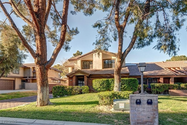 view of front facade featuring stucco siding, a tiled roof, decorative driveway, a front yard, and brick siding