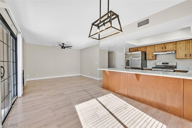 kitchen featuring a breakfast bar area, appliances with stainless steel finishes, kitchen peninsula, pendant lighting, and ceiling fan