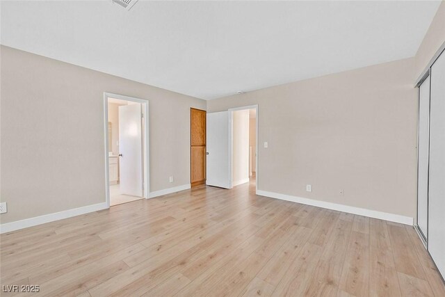 unfurnished bedroom with a closet, connected bathroom, and light hardwood / wood-style flooring