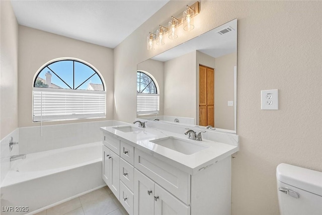 bathroom featuring tile patterned floors, toilet, vanity, and a tub