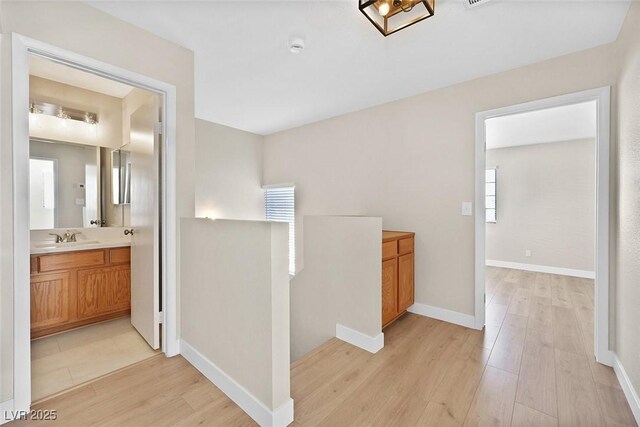 hallway with sink, light hardwood / wood-style flooring, and a healthy amount of sunlight