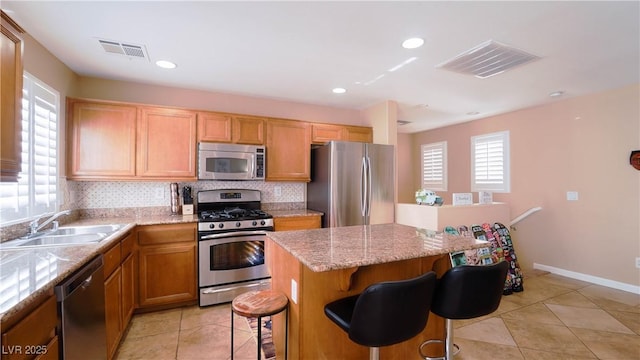 kitchen featuring sink, appliances with stainless steel finishes, a kitchen breakfast bar, a kitchen island, and decorative backsplash