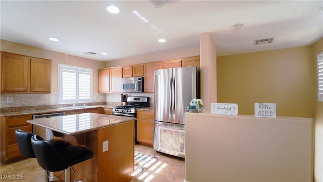 kitchen featuring a breakfast bar, appliances with stainless steel finishes, a center island, and backsplash