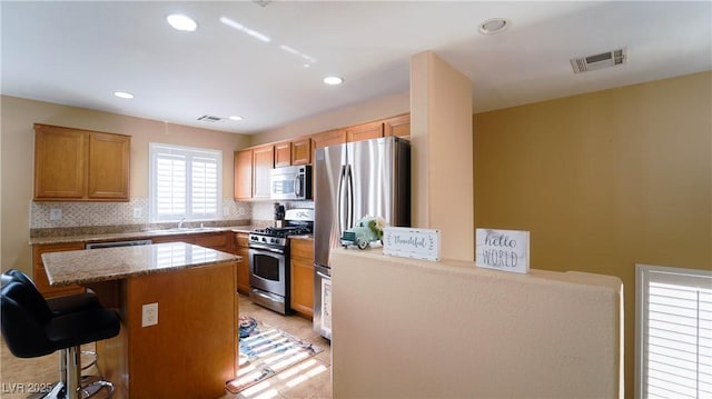 kitchen featuring a kitchen island, a breakfast bar, sink, backsplash, and stainless steel appliances