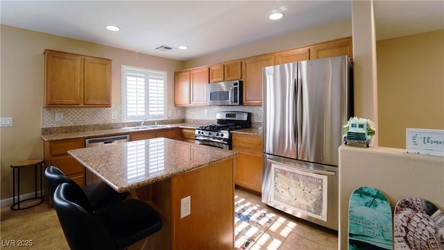 kitchen with sink, tasteful backsplash, a kitchen breakfast bar, a kitchen island, and stainless steel appliances