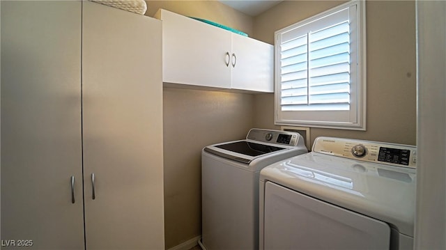 laundry area with separate washer and dryer and cabinets