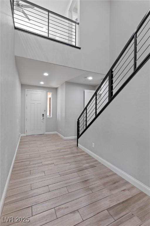 entryway featuring a healthy amount of sunlight, light wood-type flooring, and a towering ceiling