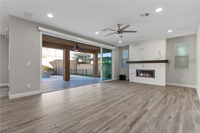 unfurnished living room with ceiling fan, a fireplace, and light hardwood / wood-style flooring