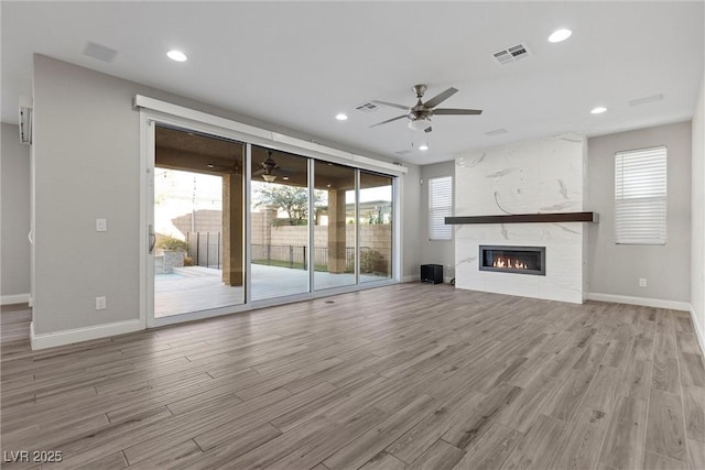 unfurnished living room featuring a wealth of natural light, a high end fireplace, and light hardwood / wood-style flooring