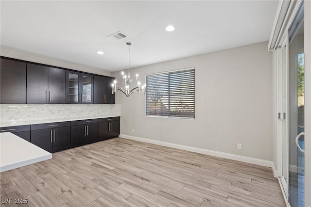 unfurnished dining area with an inviting chandelier and light hardwood / wood-style flooring