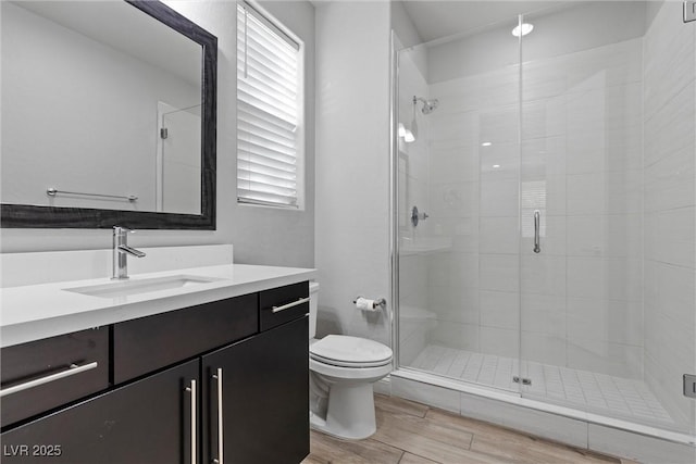 bathroom with vanity, toilet, an enclosed shower, and wood-type flooring