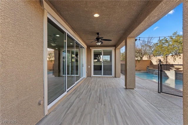 wooden deck with ceiling fan and a fenced in pool