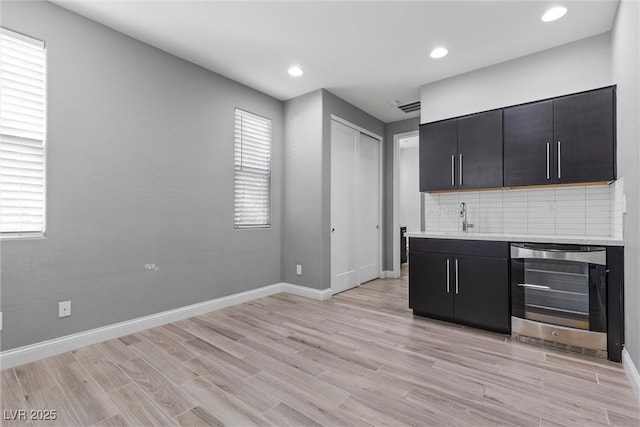 kitchen with a healthy amount of sunlight, sink, wine cooler, and light hardwood / wood-style floors