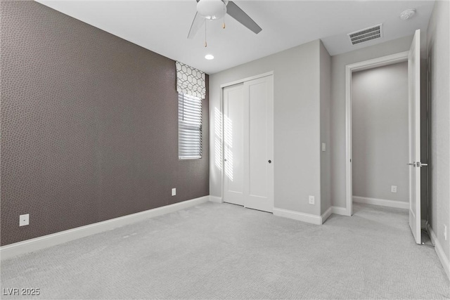 unfurnished bedroom featuring ceiling fan, light colored carpet, and a closet