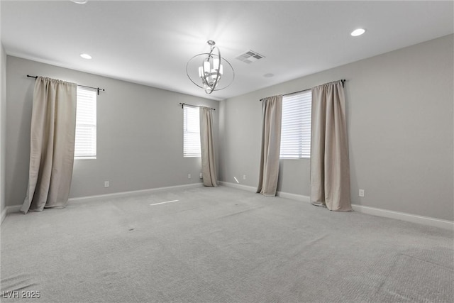 empty room with light carpet and a notable chandelier