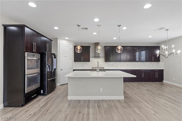 kitchen with sink, double oven, dark brown cabinetry, decorative light fixtures, and black refrigerator with ice dispenser