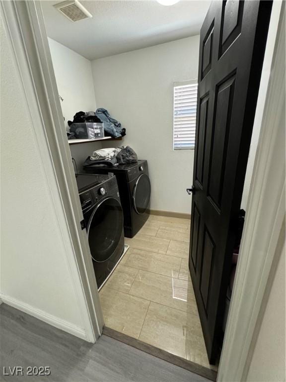 laundry area with independent washer and dryer and light hardwood / wood-style flooring