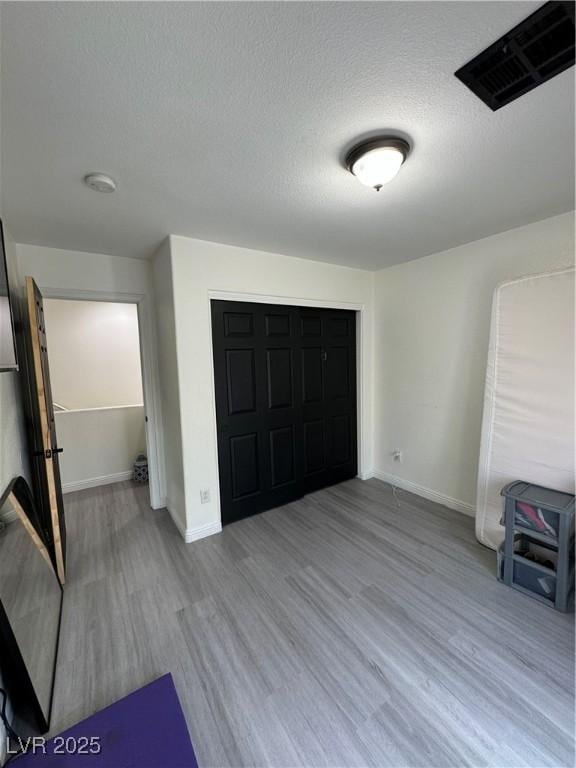 unfurnished bedroom featuring a textured ceiling and light hardwood / wood-style flooring