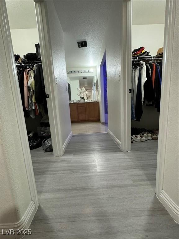 corridor featuring light hardwood / wood-style floors and a textured ceiling