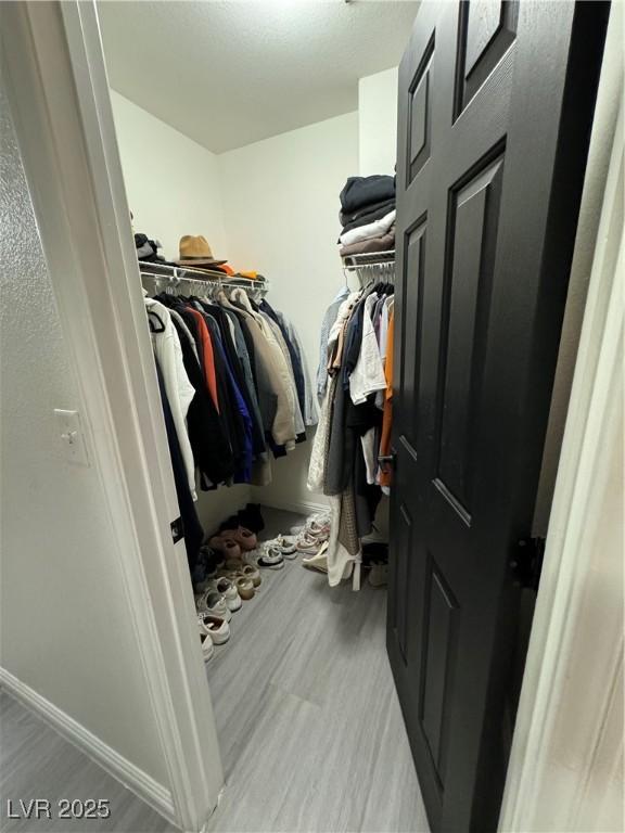 walk in closet with light hardwood / wood-style floors