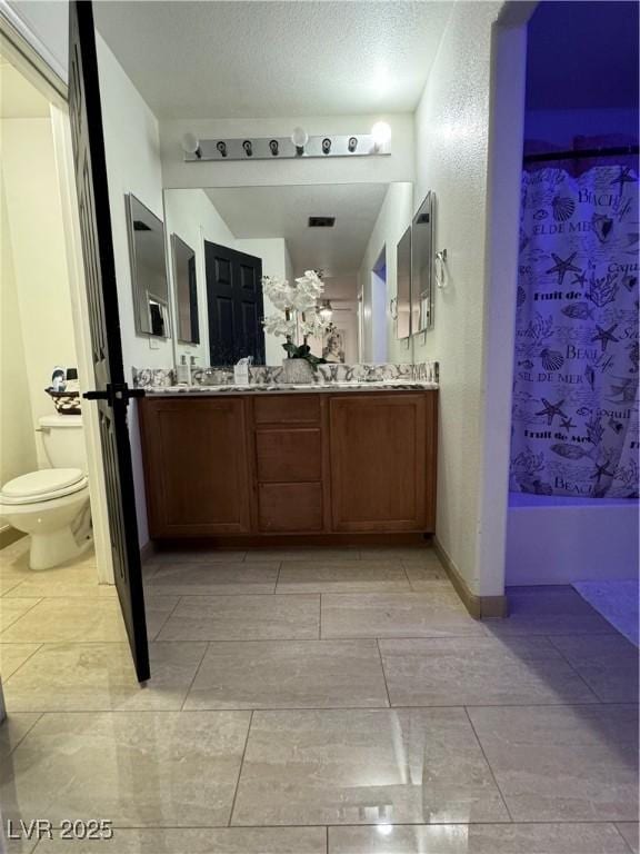 bathroom featuring vanity, a textured ceiling, and toilet