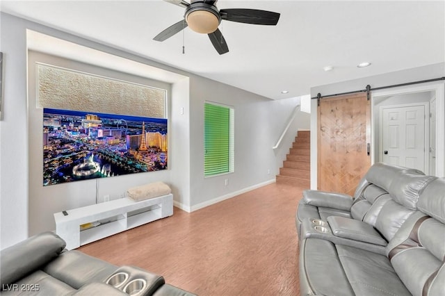 living room featuring ceiling fan, a barn door, and hardwood / wood-style floors