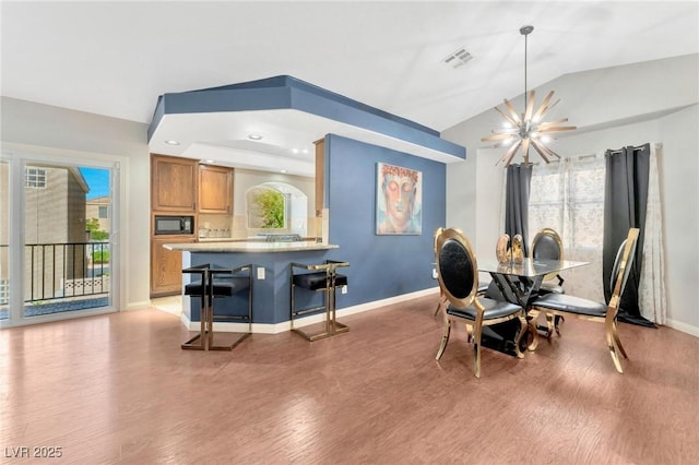 dining area featuring lofted ceiling, a chandelier, and light hardwood / wood-style flooring