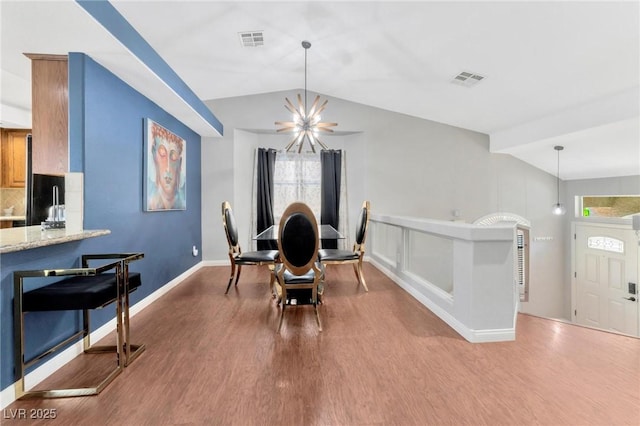 dining area with lofted ceiling, hardwood / wood-style floors, and a notable chandelier