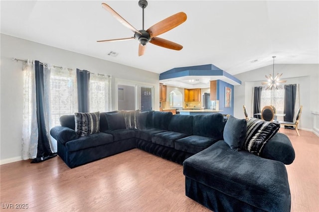 living room featuring lofted ceiling, ceiling fan with notable chandelier, and wood-type flooring