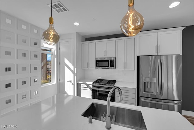 kitchen featuring white cabinetry, stainless steel appliances, sink, and pendant lighting